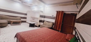 Una habitación con cama, sofá, una mesita y una estantería empotrada.