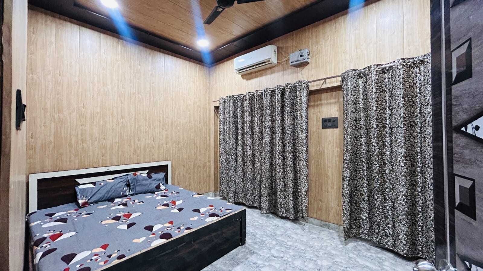 A bedroom with a bed, curtains, an air conditioning unit, and a ceiling fan.