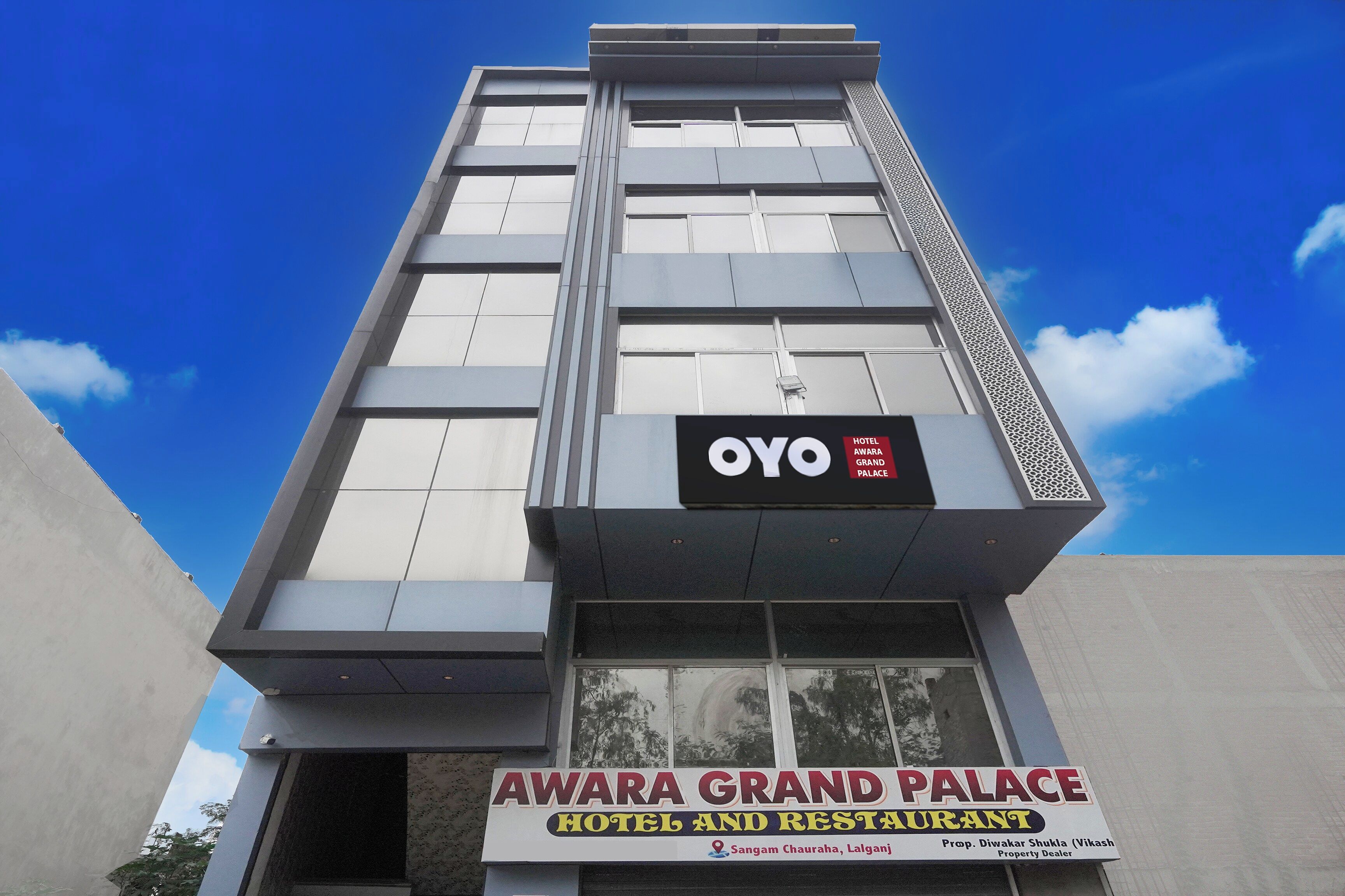 A hotel with a sign for 'AWAREA GRAND PALACE HOTEL AND RESTAURANT' and a smaller sign for 'OYO HOTEL AWAREA GRAND PALACE'.