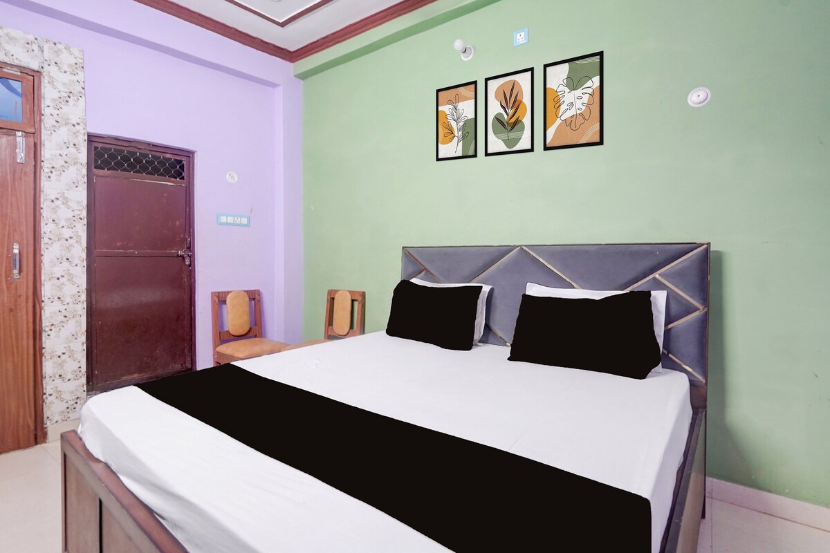 Un dormitorio con una cama, una puerta de madera y una pared con tres cuadros enmarcados.