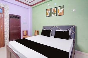 Un dormitorio con una cama, una puerta de madera y una pared con tres cuadros enmarcados.