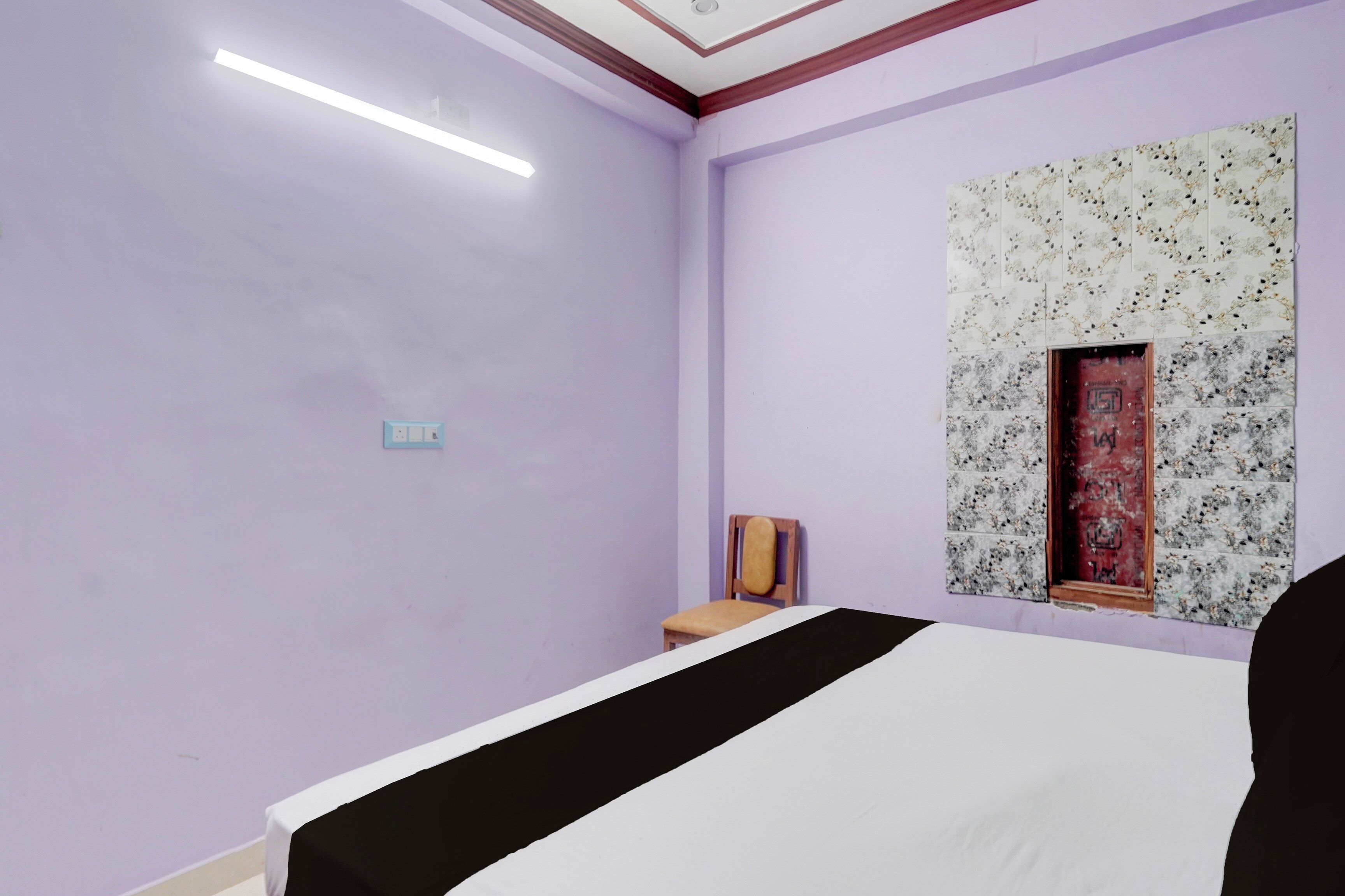 A room with a bed, a chair, a wall-mounted artwork, and a door.