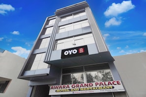 Un edificio de varios pisos con un letrero que dice 'AWARE GRAND PALACE HOTEL AND RESTAURANT' y un letrero más pequeño que indica 'OYO HOTEL AWARE GRAND PALACE'.
