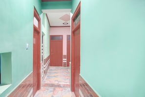 Un pasillo con piso de baldosas, puertas de madera y una escalera que sube a un nivel superior.