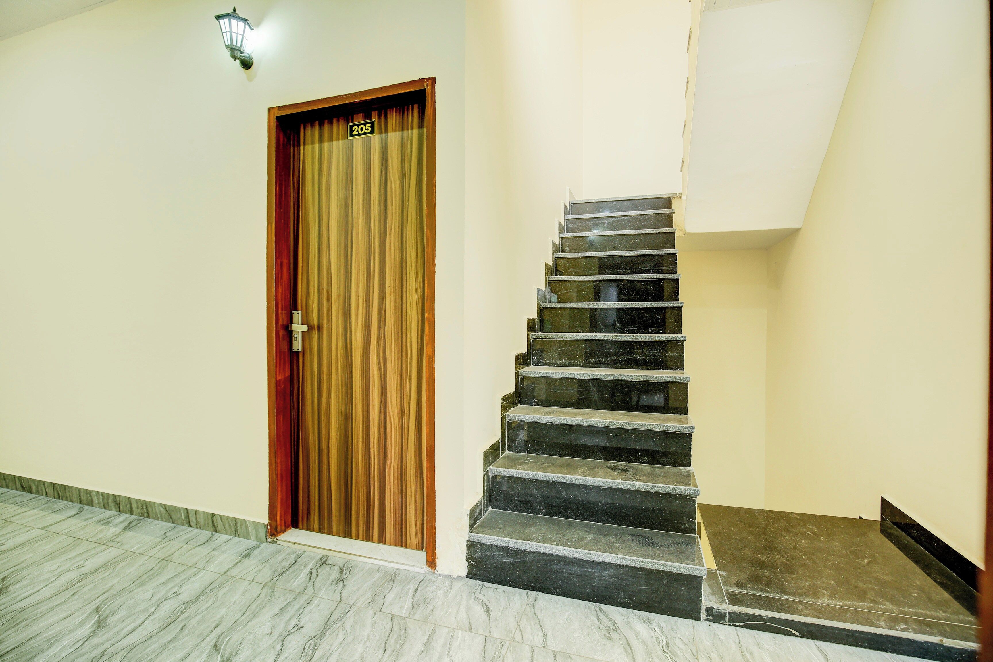Una escalera con una puerta de madera marcada con el número '205' y una lámpara colgando sobre ella.