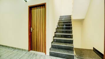 Una escalera con una puerta de madera marcada con el número '205' y una lámpara colgando sobre ella.