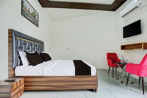 Une chambre d’hôtel avec un lit, un bureau, une chaise, une télévision et un tableau au mur.