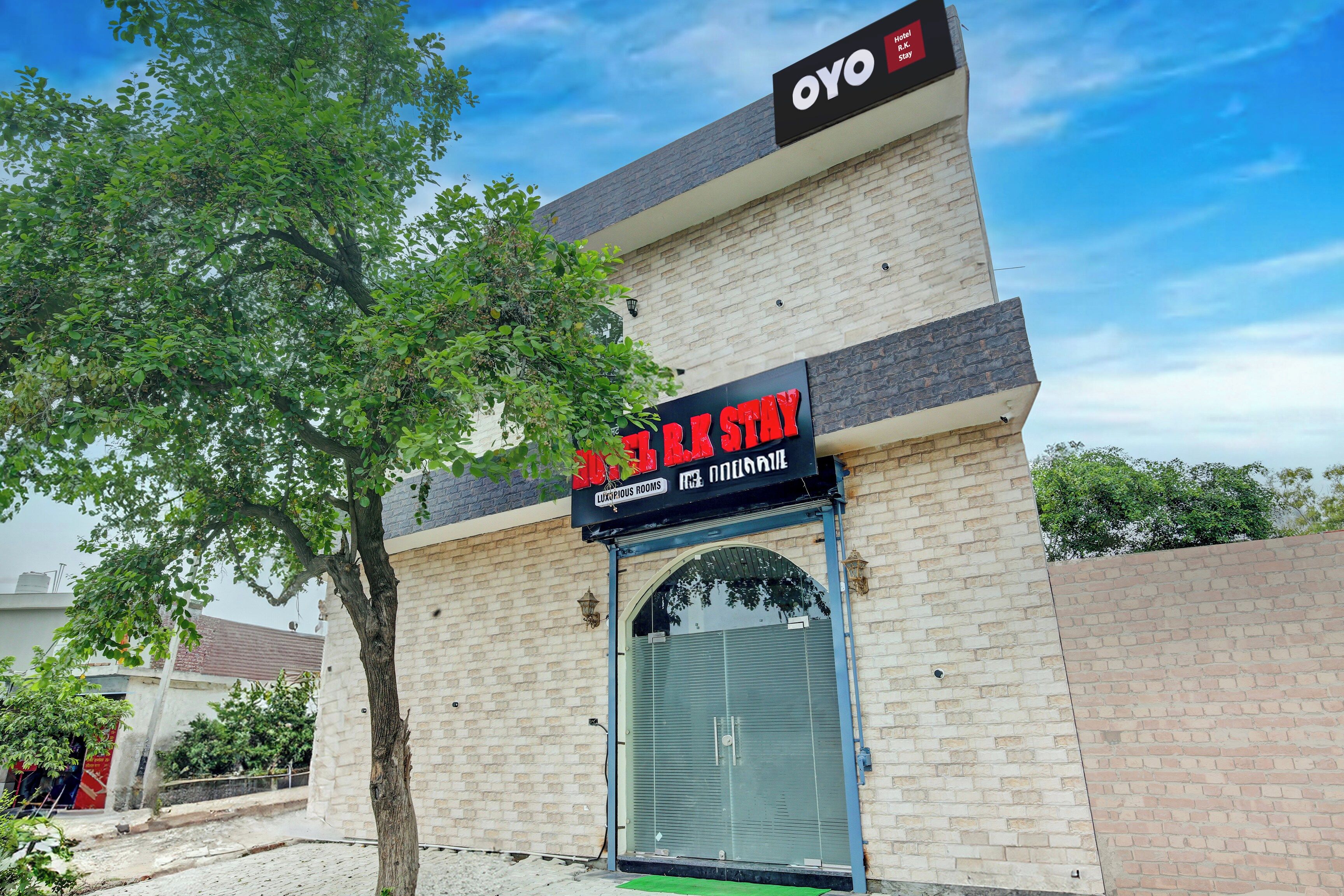 Un hotel llamado 'OYO R.K Stay' con un letrero que indica 'HABITACIONES LUSOSAS'.