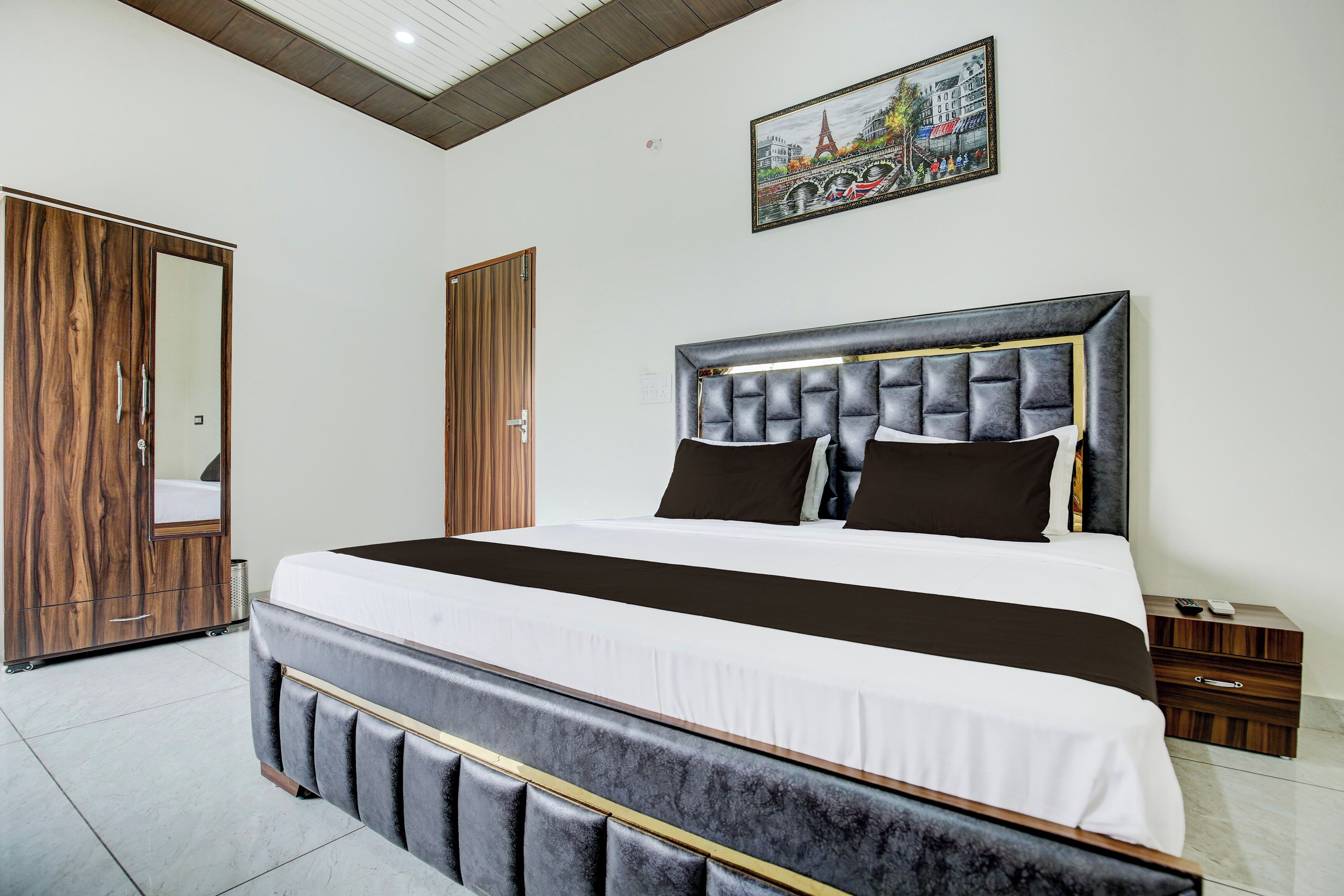 Un dormitorio con una cama grande, un armario de madera y un cuadro en la pared.