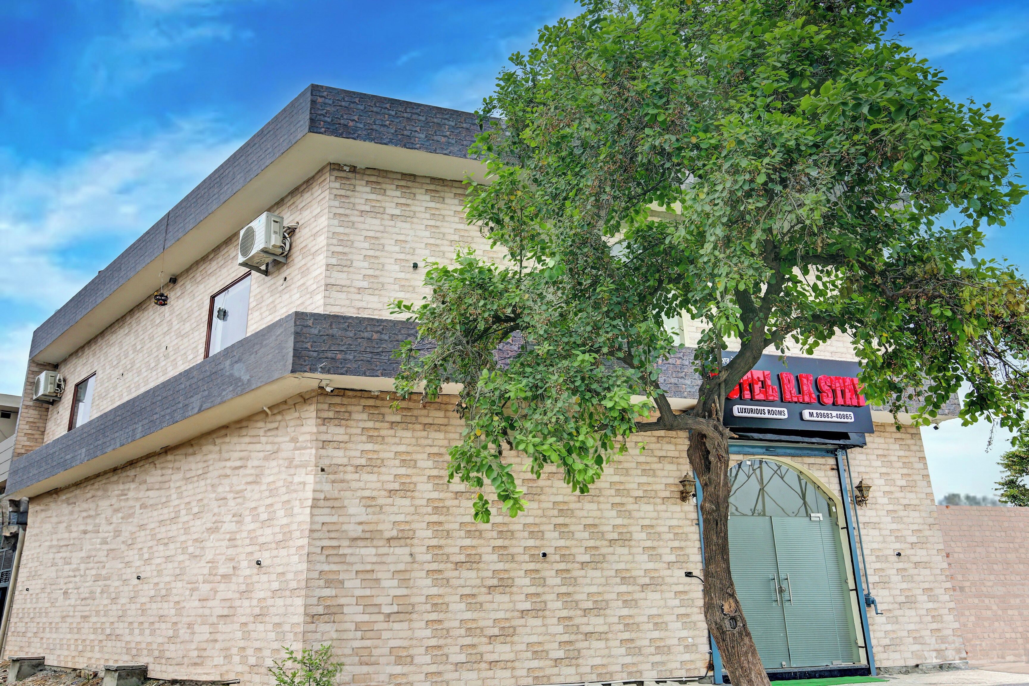 A building with a brick facade, a tree in front, and a sign for 'Hotel Star' with a mention of 'luxurious rooms.'