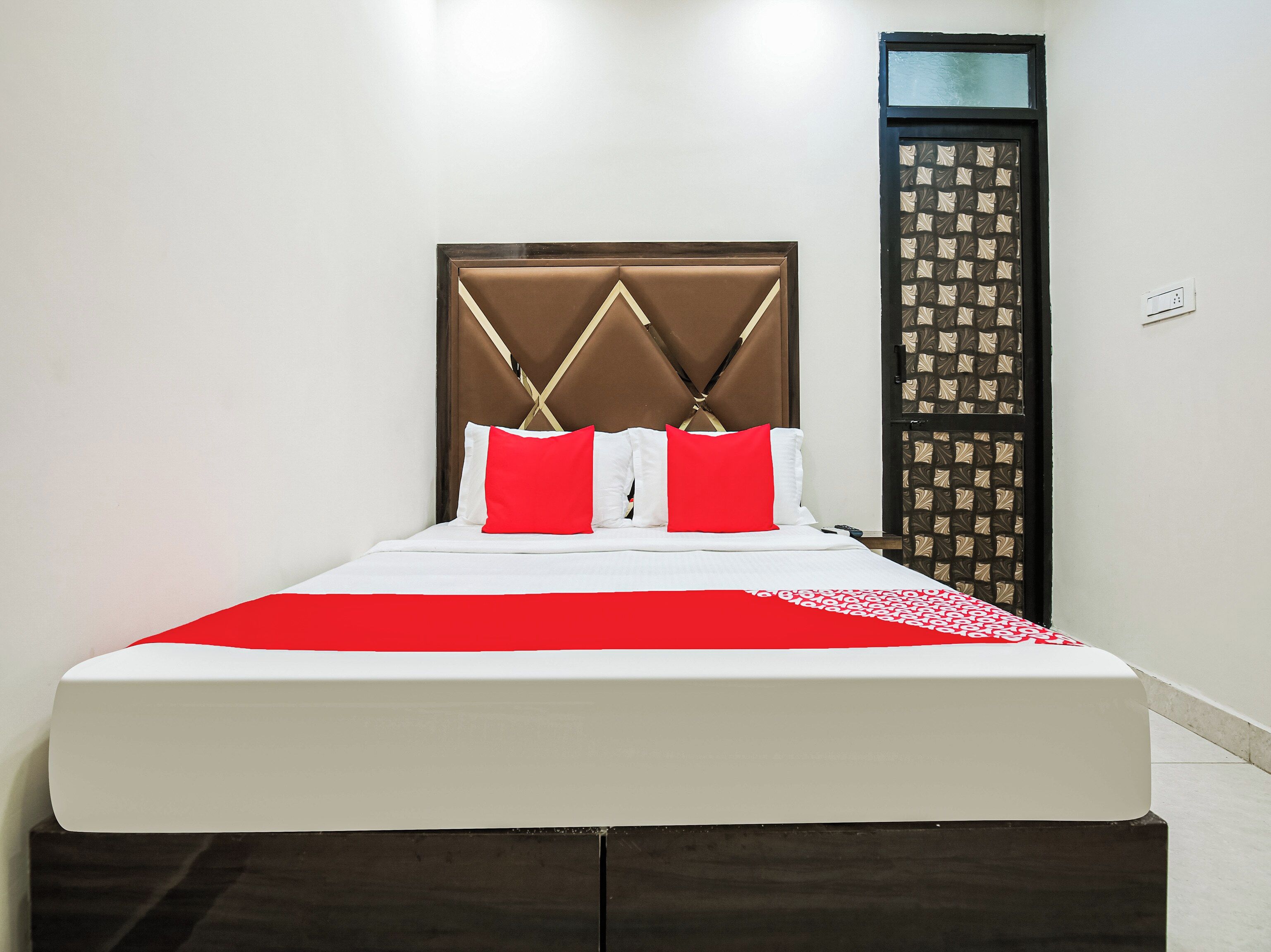 A bed with a headboard, white bedding, and red pillows.
