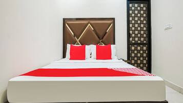A bed with a headboard, white bedding, and red pillows.