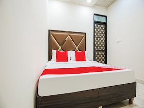 A bed with a headboard, white bedding, and a red accent pillow. - Hotel O by OYO Sunrise (Ludhiana)
