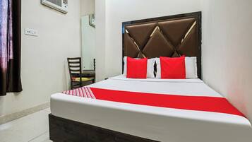 A hotel room with a bed, a chair, a mirror, and an air conditioning unit.