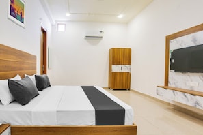 A hotel room with a bed, a wardrobe, a television, and an air conditioning unit. - Hotel O by OYO GRAND STAY (Ludhiana)