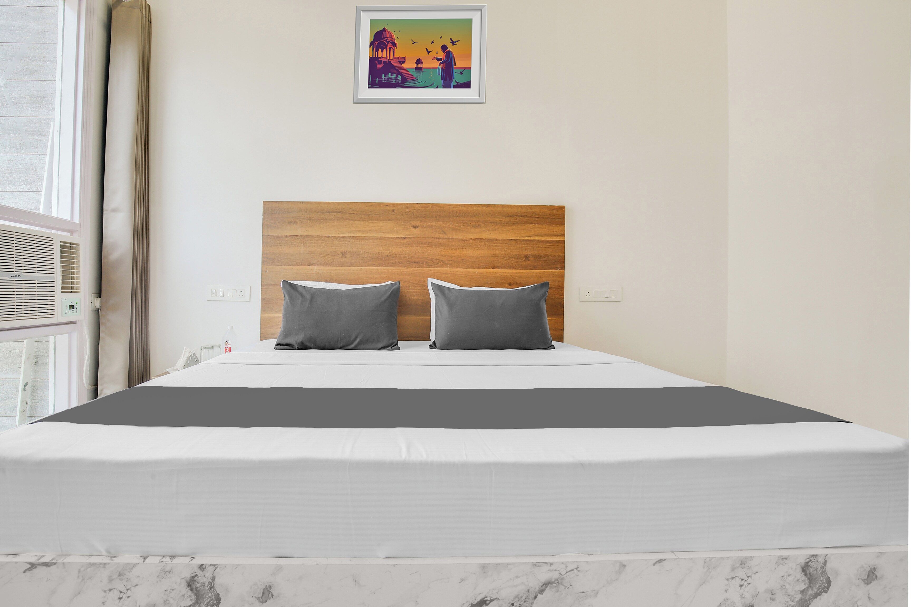 A bed with a wooden headboard, two pillows, and a white mattress in a room with a marble floor.
