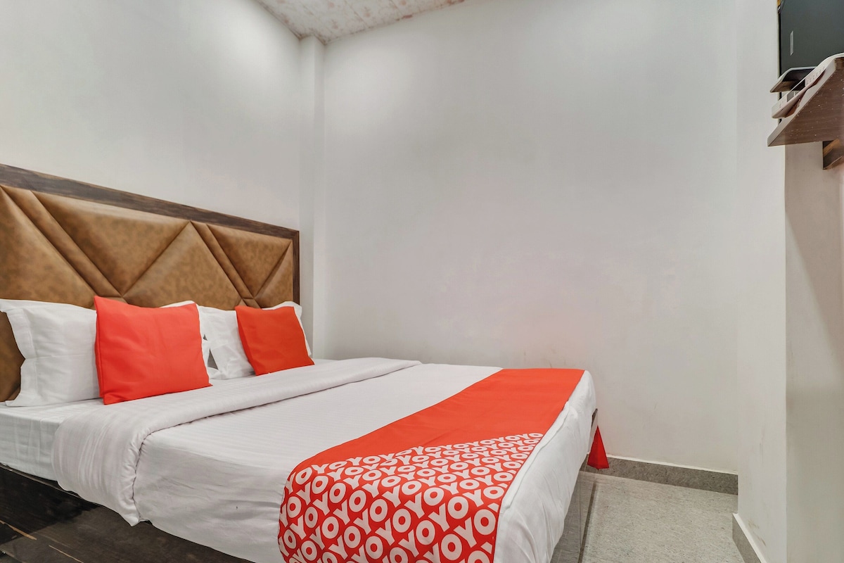 A hotel room with a bed, pillows, and a headboard.