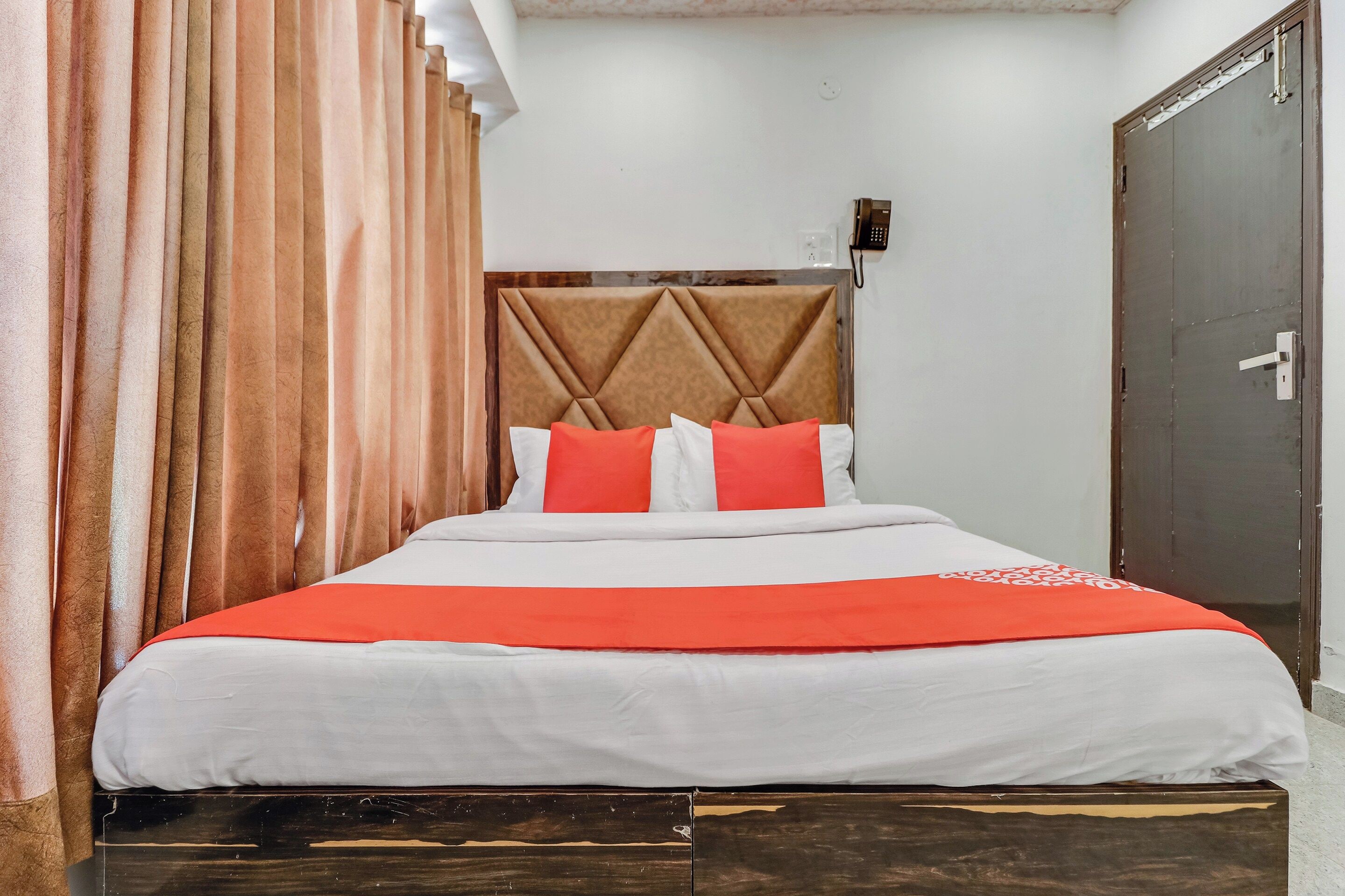 Una habitación de hotel con cama, cortinas, armario y puerta.