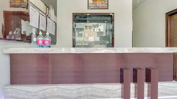 Un comptoir d’accueil avec un plateau en marbre, un tableau encadré au-dessus et une fenêtre donnant sur des immeubles.