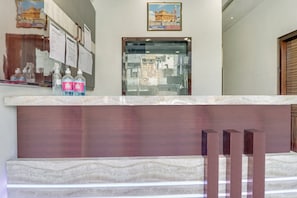 A reception desk with a marble top, a framed picture above, and a window with a view of buildings. - Hotel O by OYO Sun View (Ludhiana)