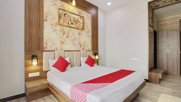 A bedroom with a large bed, wooden headboard, two bedside lamps, a floral wall decoration, and a wardrobe.