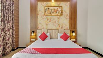 A hotel room with a large bed, floral wallpaper, a framed picture on the wall, and bedside lamps.