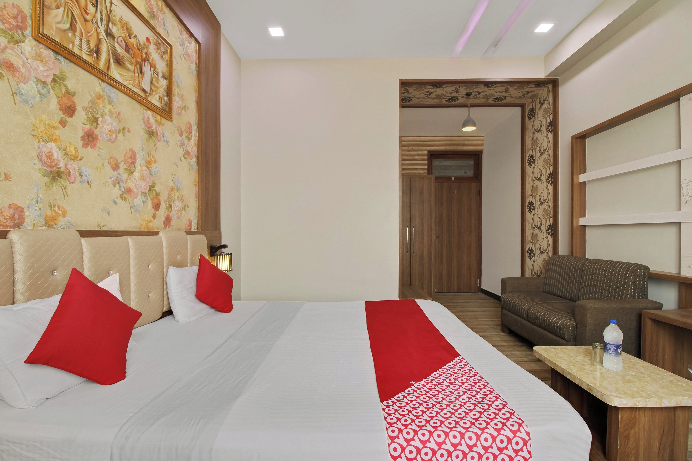 A hotel room with a bed, a sofa, a desk, and a door leading to another room.