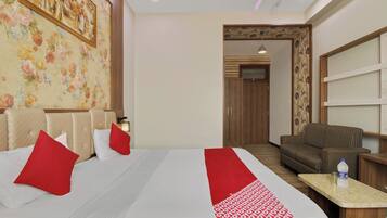 A hotel room with a bed, a sofa, a desk, and a door leading to another room.