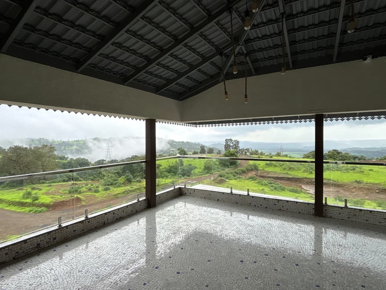 A spacious room with a high ceiling, large windows, and a view of a green landscape.