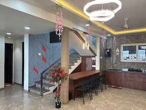 A modern kitchen with a central island, a staircase, and a dining area with chairs.