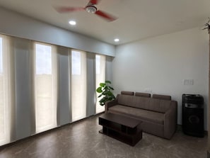 Ein Wohnzimmer mit einer Couch, einem Couchtisch, einer Pflanze und einem Lautsprecher.