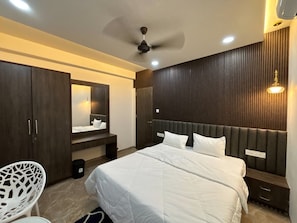 A modern bedroom with a large bed, a wardrobe, a mirror, and a ceiling fan.
