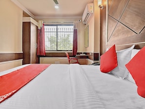 Een hotelkamer met een bed, een raam met uitzicht, een bureau en een stoel.