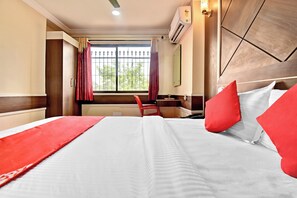 Una habitación de hotel con una cama grande, un escritorio y una ventana con cortinas.