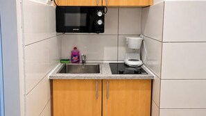 A compact kitchen with a microwave, coffee maker, and a sink. - One More Night in Vienna 1BR and Living Room (Vienna)
