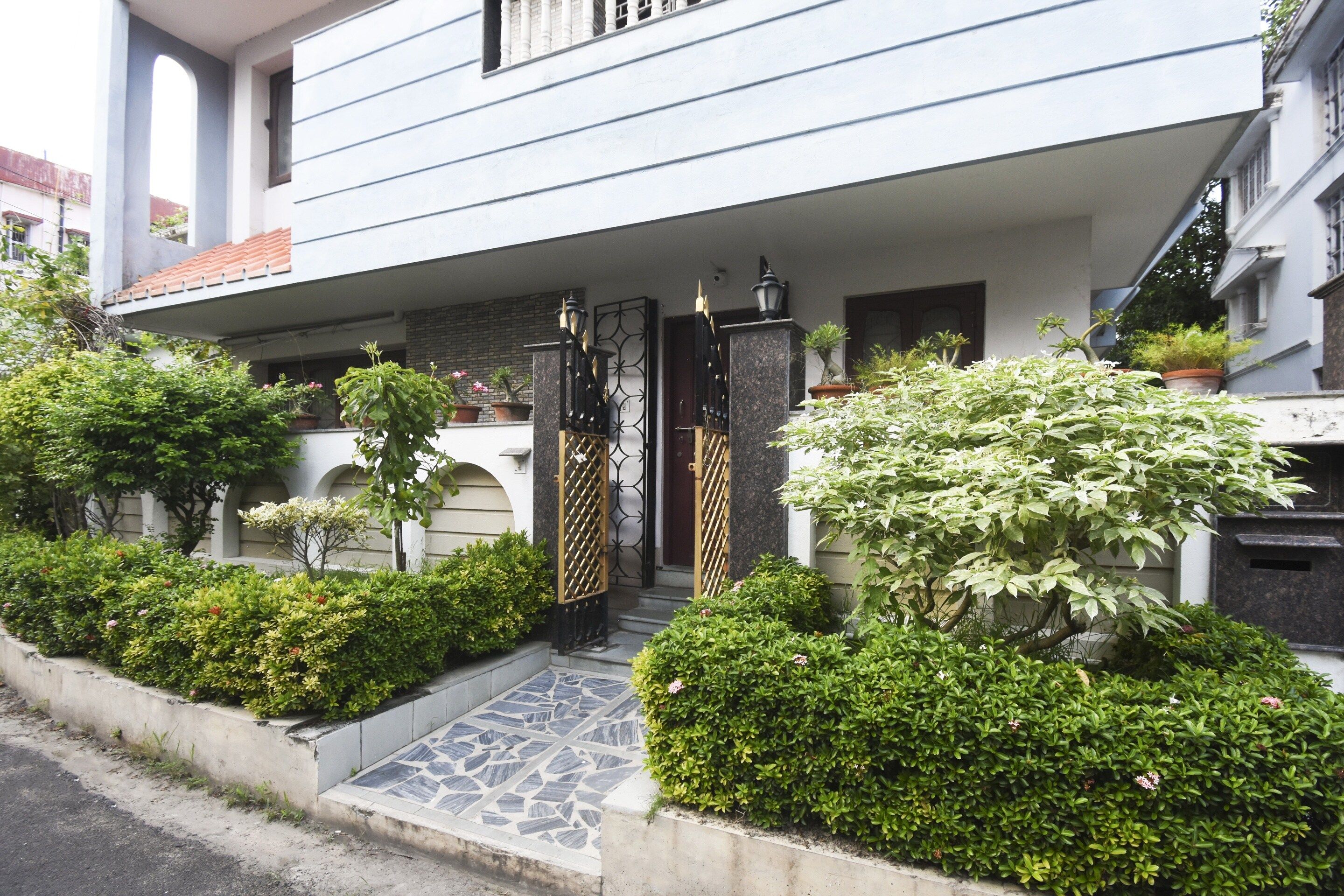 Un edificio residencial con acceso empedrado, un camino de entrada con portón y zonas verdes cuidadas.