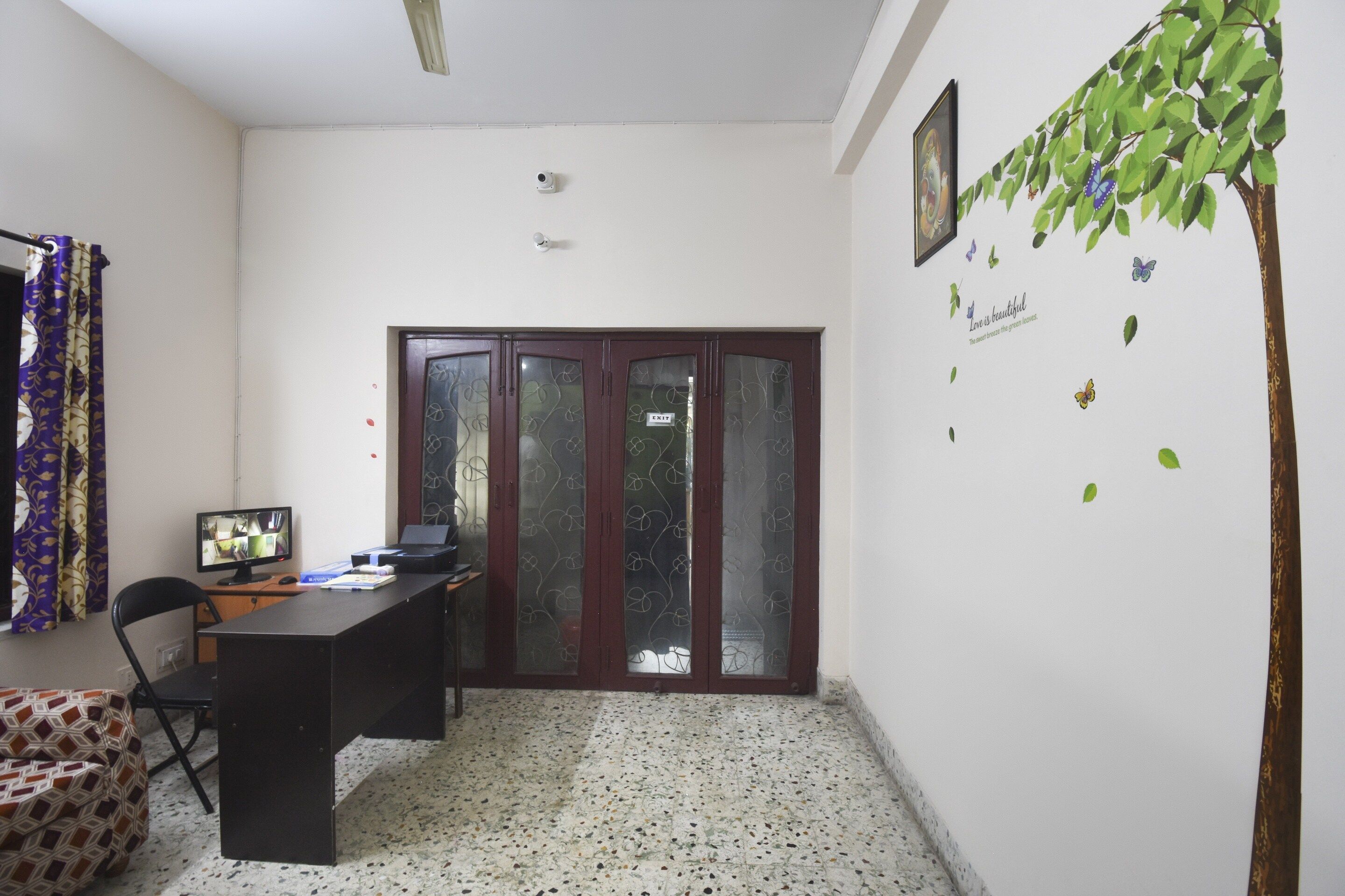 A room with a desk, computer, chair, and a door with an 'EXIT' sign.