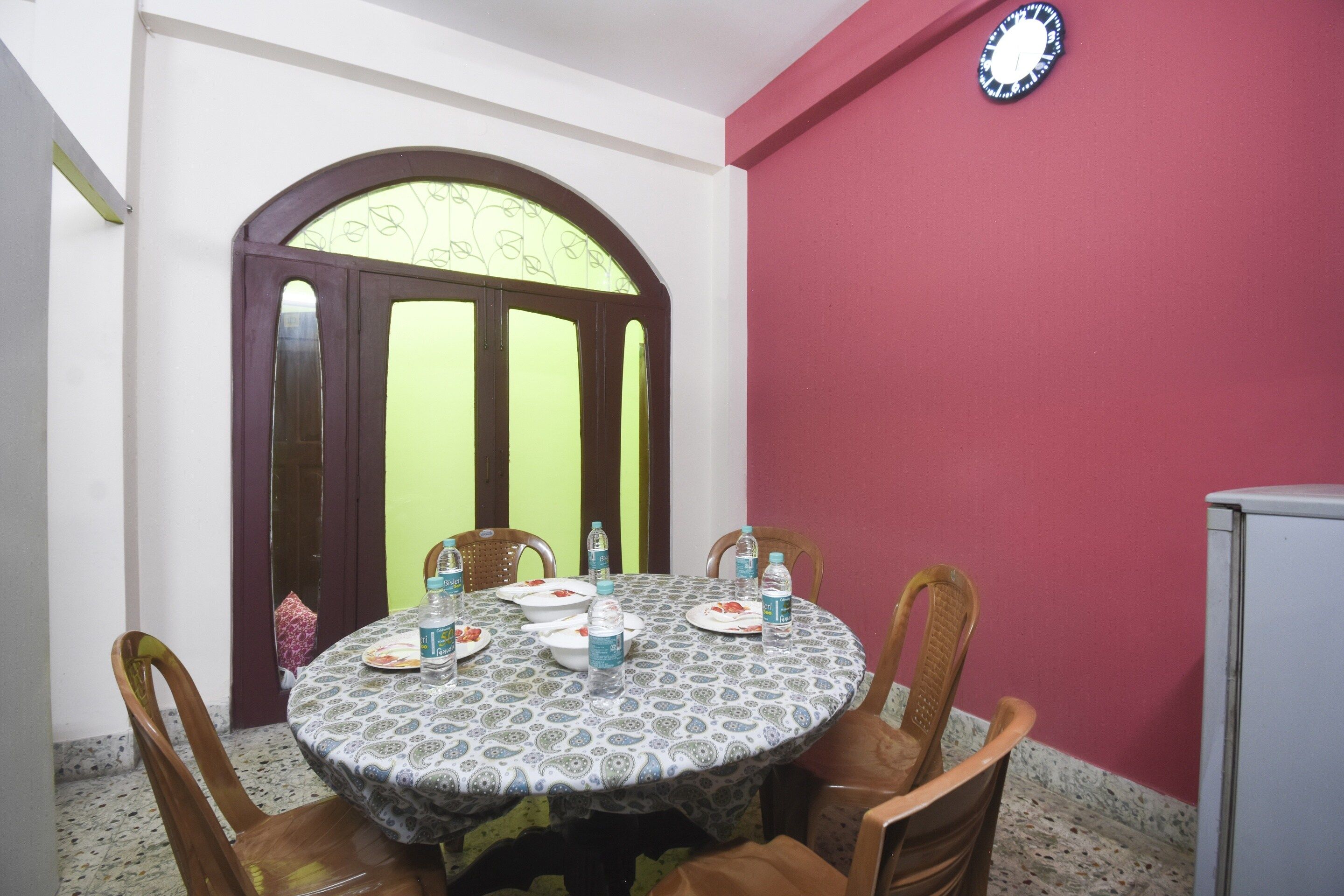 A dining area with a round table, chairs, plates, bowls, and water bottles.