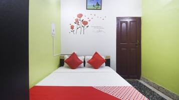 Una habitación con una cama, una puerta y una pared decorada con un adhesivo floral y una pequeña fotografía.