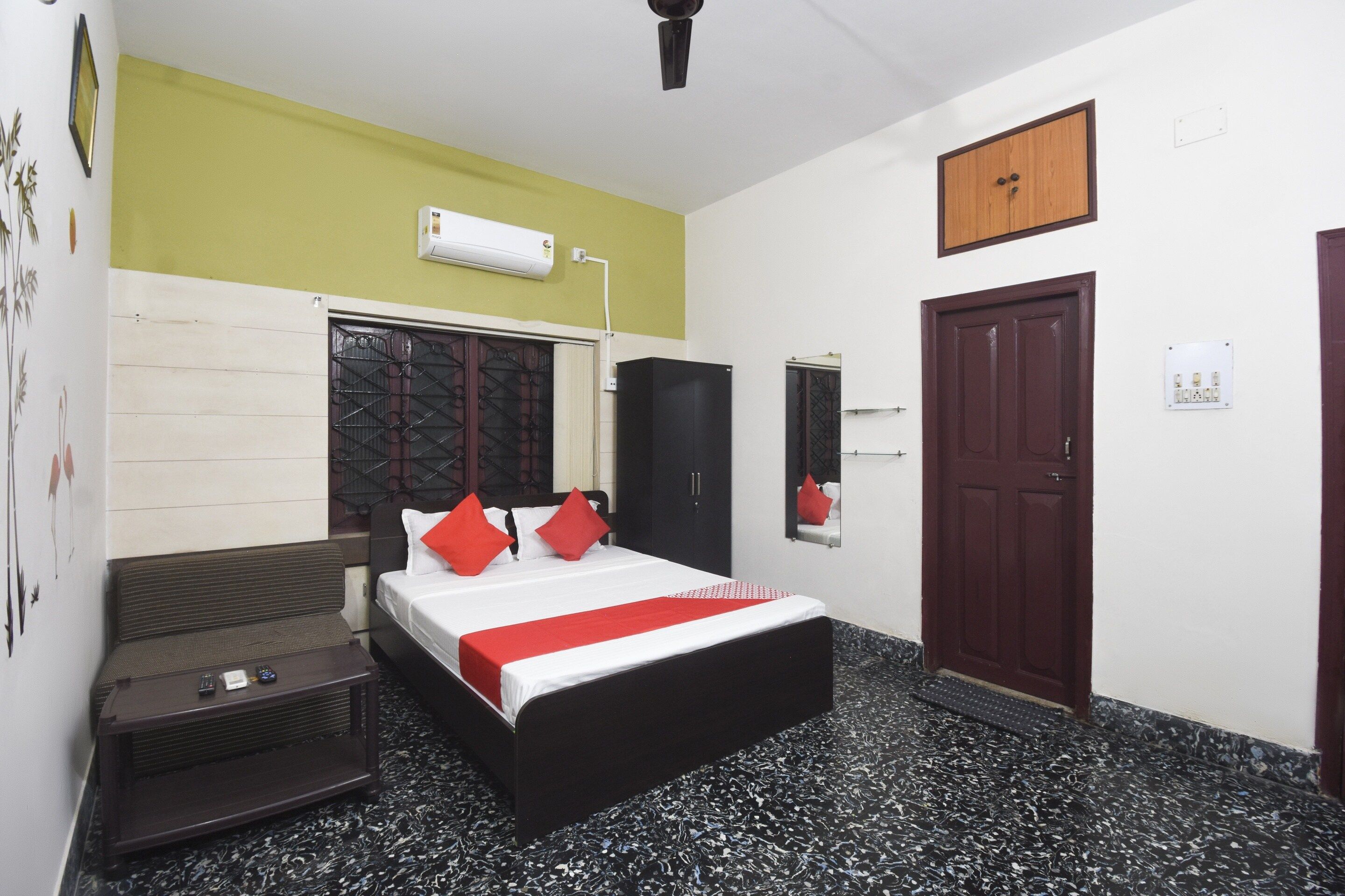 Habitación de hotel con cama, armario, escritorio, espejo y puerta.