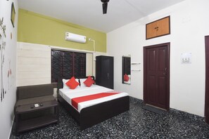 A hotel room with a bed, a wardrobe, a desk, a mirror, and a door. - Hotel O Smriti Villa (Bidhannagar)