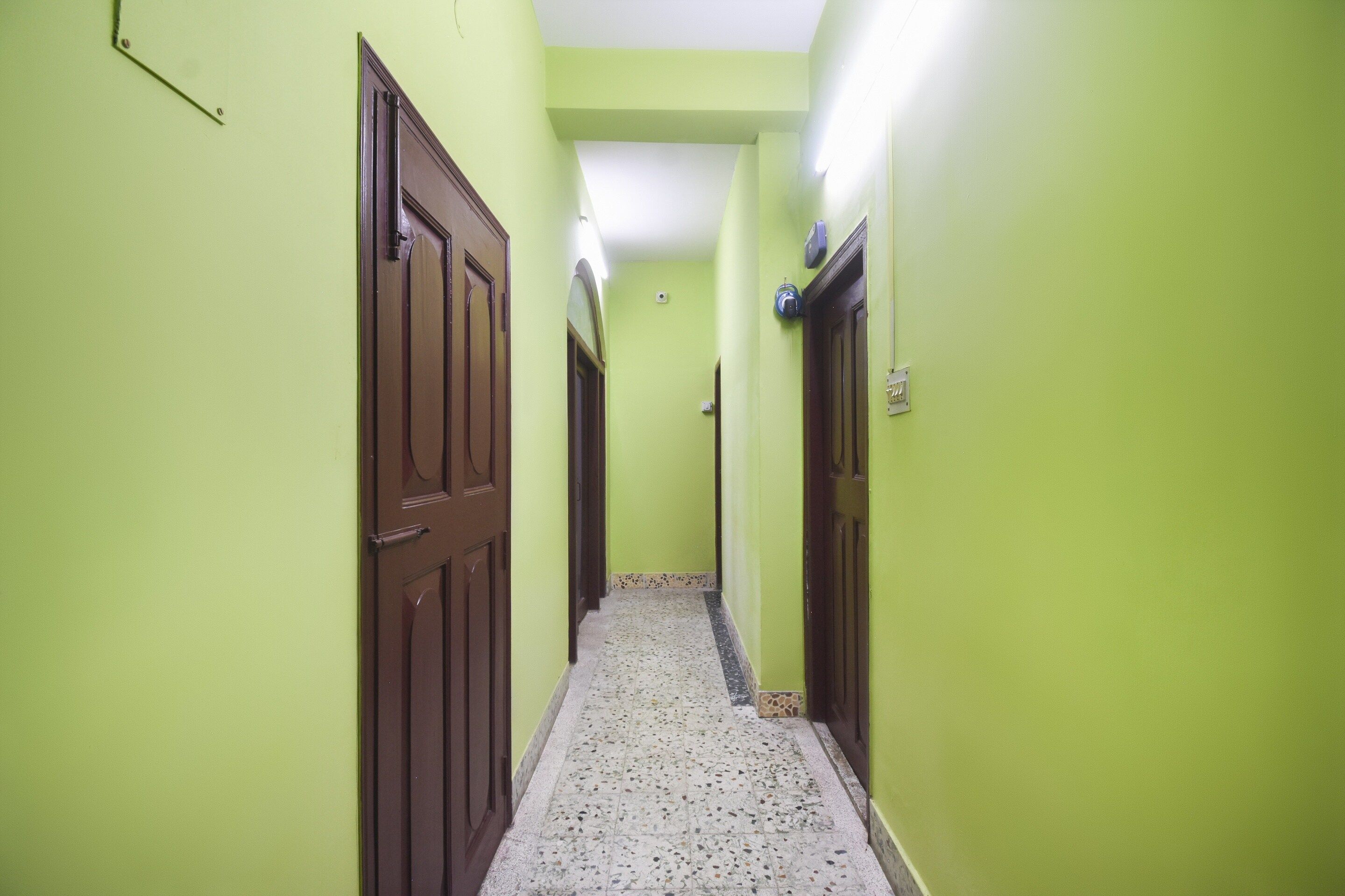 Un pasillo con paredes verdes y piso de baldosas con manchas.