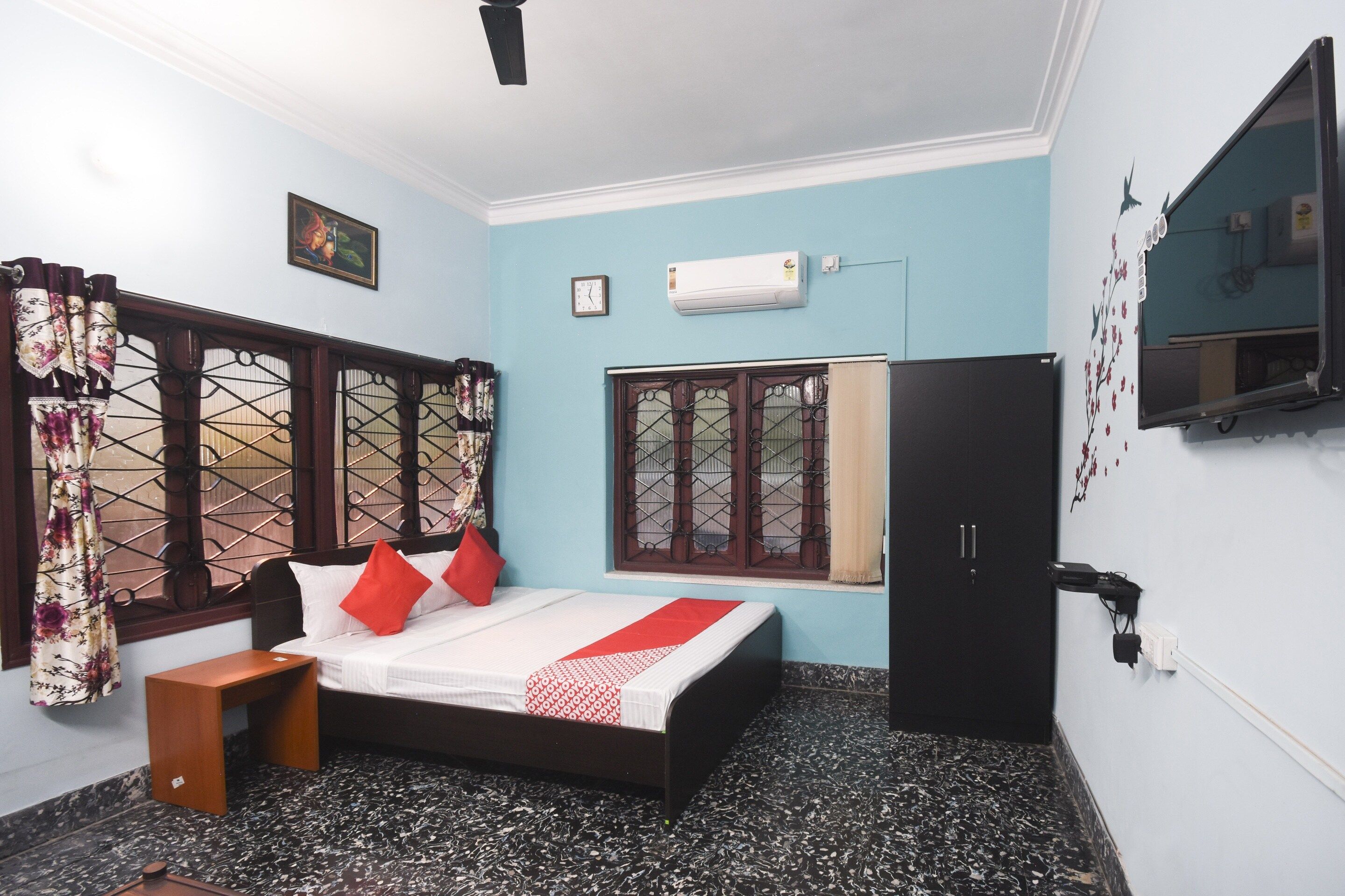 A bedroom with a bed, a wardrobe, a window with curtains, and a wall-mounted air conditioner.