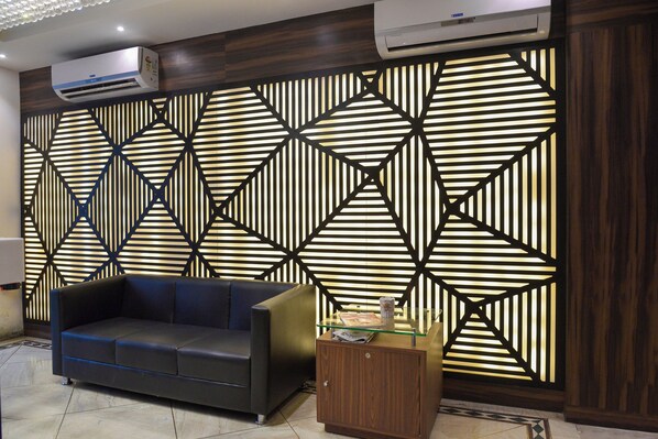 A modern living room with a geometric patterned wall, a leather sofa, and a wooden cabinet.