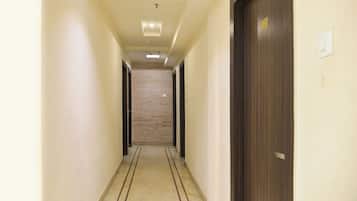 A hotel hallway with a stone wall, wooden doors, and a tiled floor.