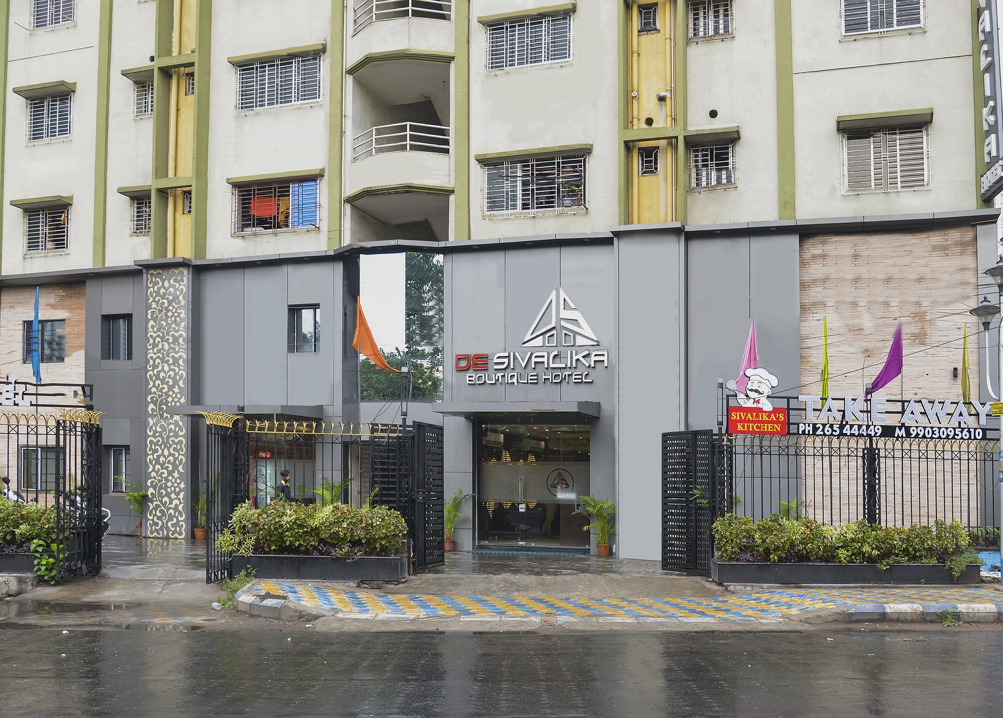 A hotel with a modern facade, multiple balconies, and a gated entrance.