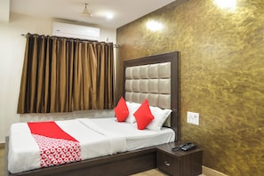A hotel room with a bed, a bedside table with a phone, and a wall-mounted air conditioner. - Collection O De Sivalika Boutique Near (Kolkata)