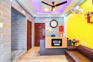 A hotel reception area with a reception desk, a clock, a ceiling fan, and a sofa. - Hotel O New KOLKATA HOTEL (Kolkata)