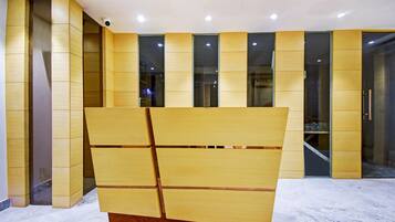 Un interior moderno con una gran estructura de madera en primer plano, iluminación empotrada e iluminación ambiental con un separador de vidrio al fondo.