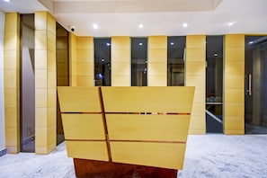 A modern interior with a large wooden structure in the foreground, recessed lighting, and a glass partition in the background. - Collection O Snowfox (Kolkata)